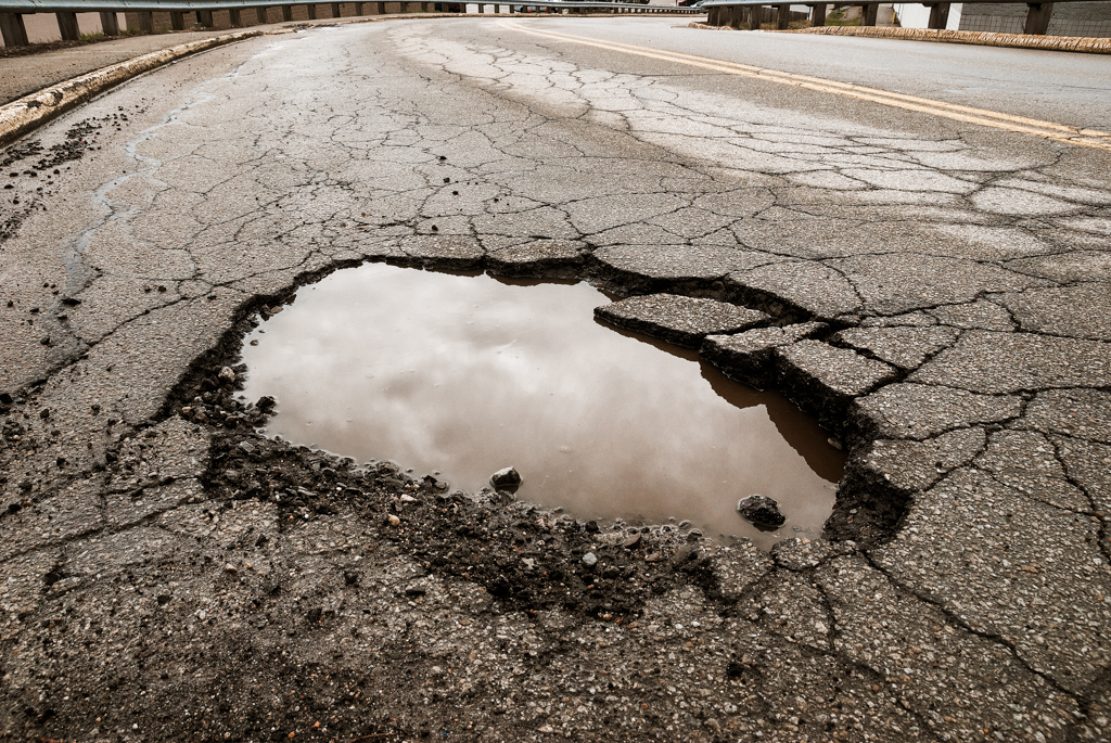 Image of a large pothole in the middle of the road