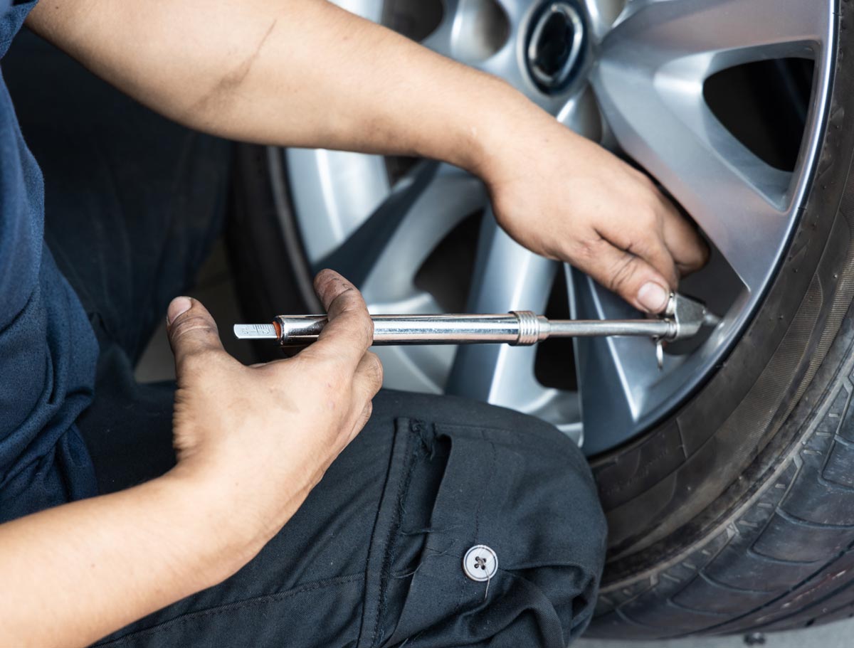 Man checking tire pressure with at home tire gauge.