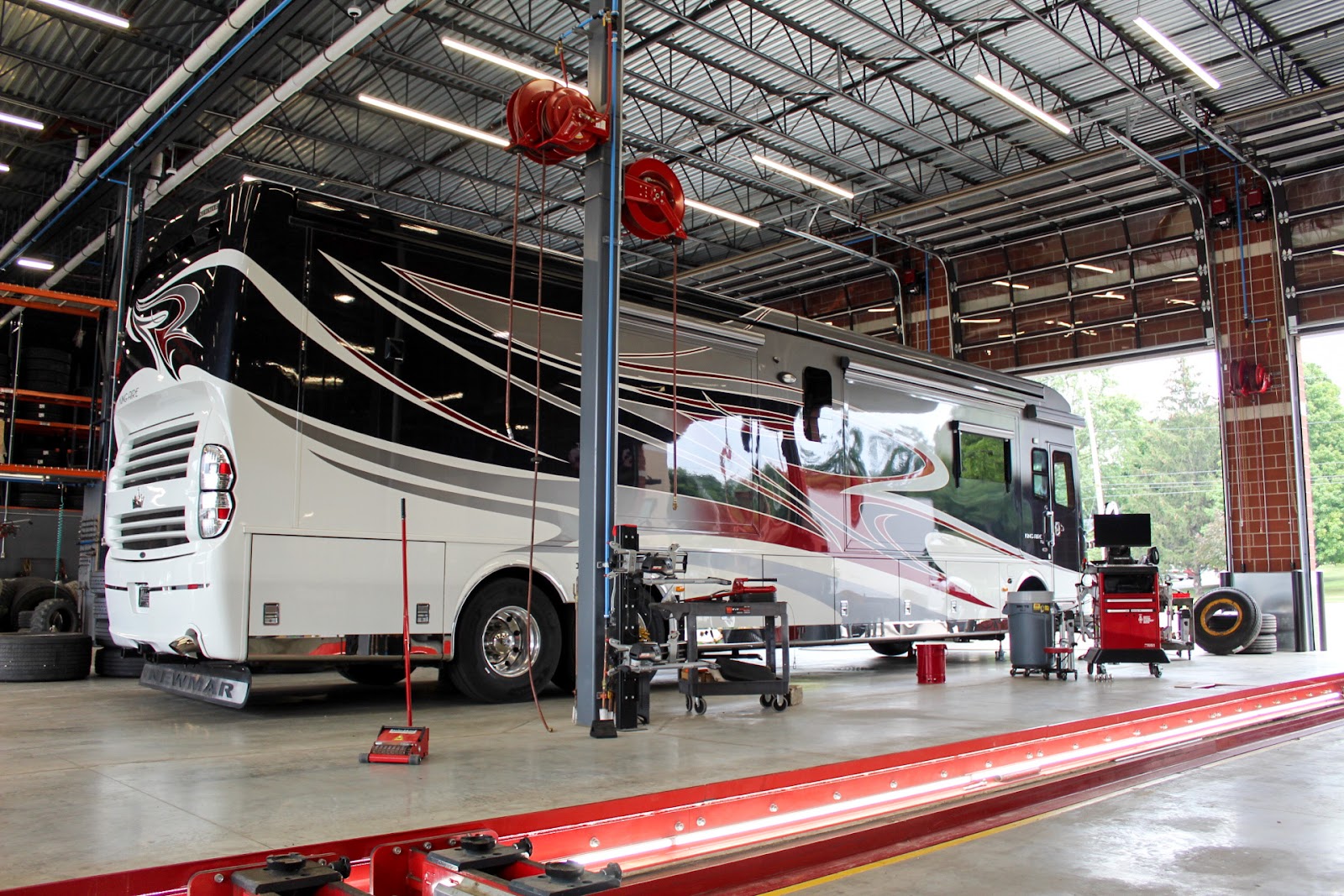 A red and black RV getting serviced at Wonderland Tire in Byron Center, MI.