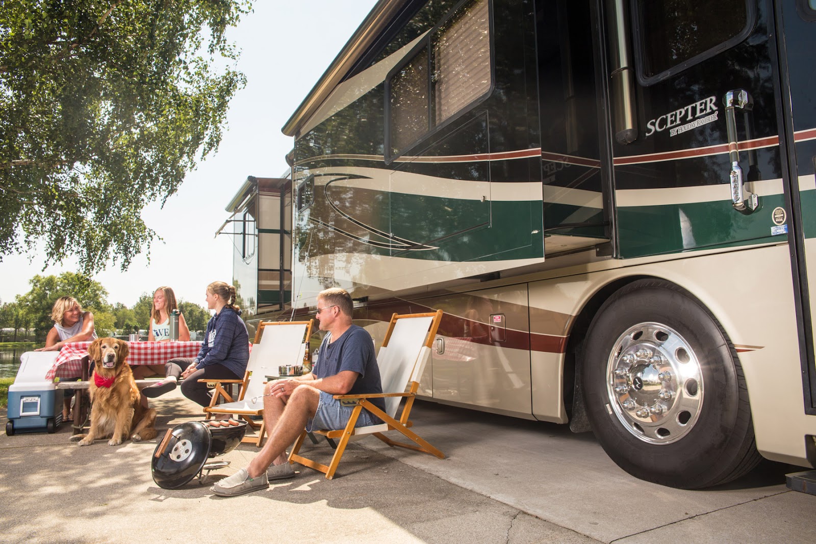  A family sitting together on their patio furniture outside of their RV while camping.