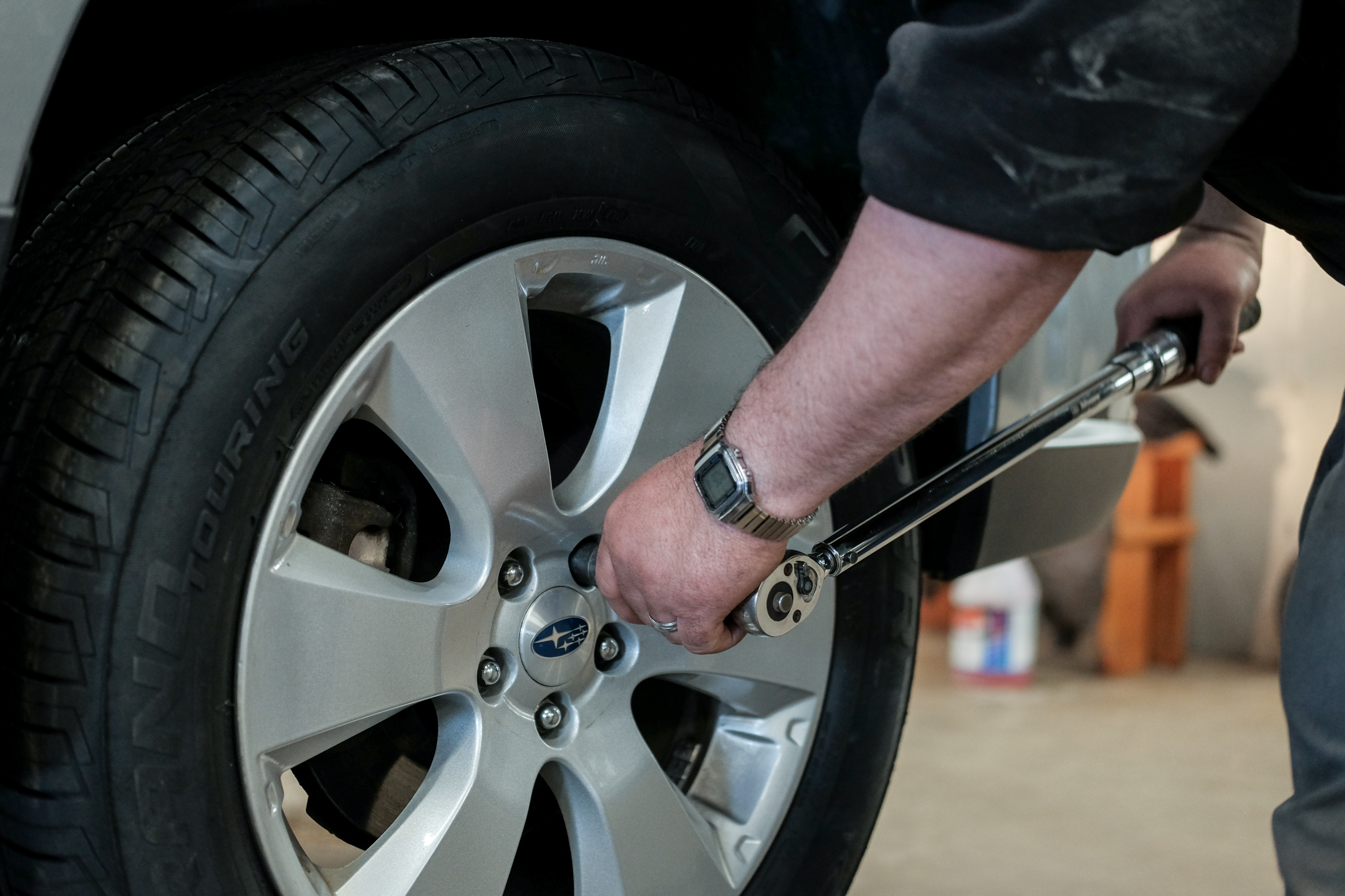 A professional Wonderland Tire technician is rotating a car's tires at their Byron Center location