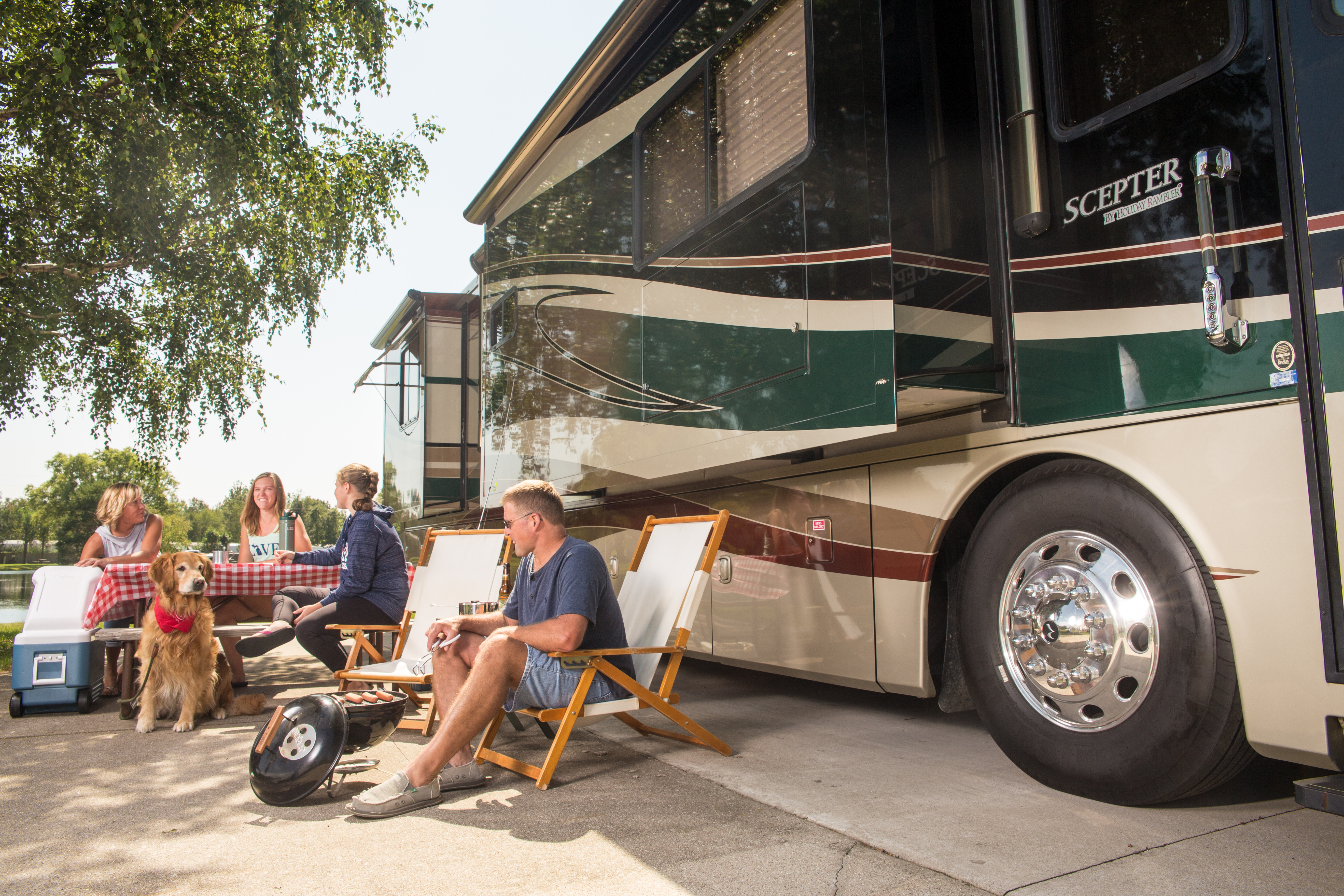 A family sitting at a picnic table in front of their RV while camping.